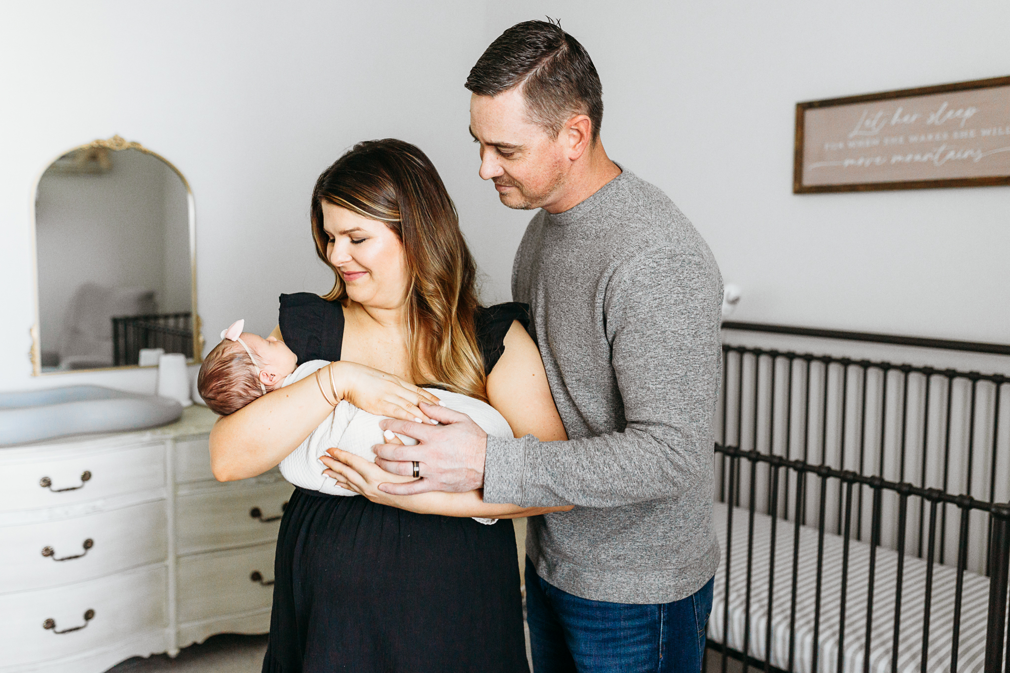 Mom and dad stand in nursery for newborn session.
