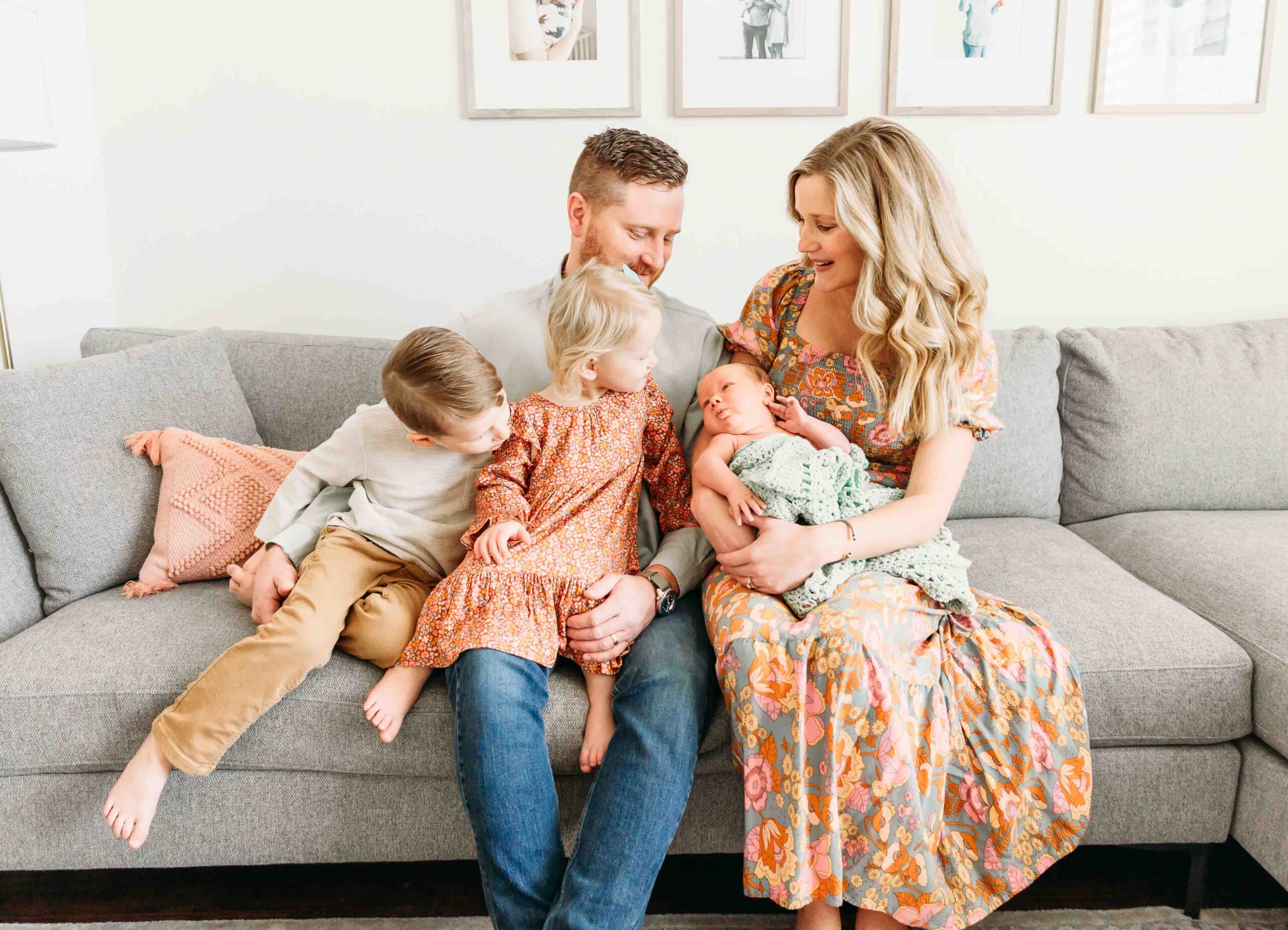 A family of 5 sits on couch during newborn photo session.