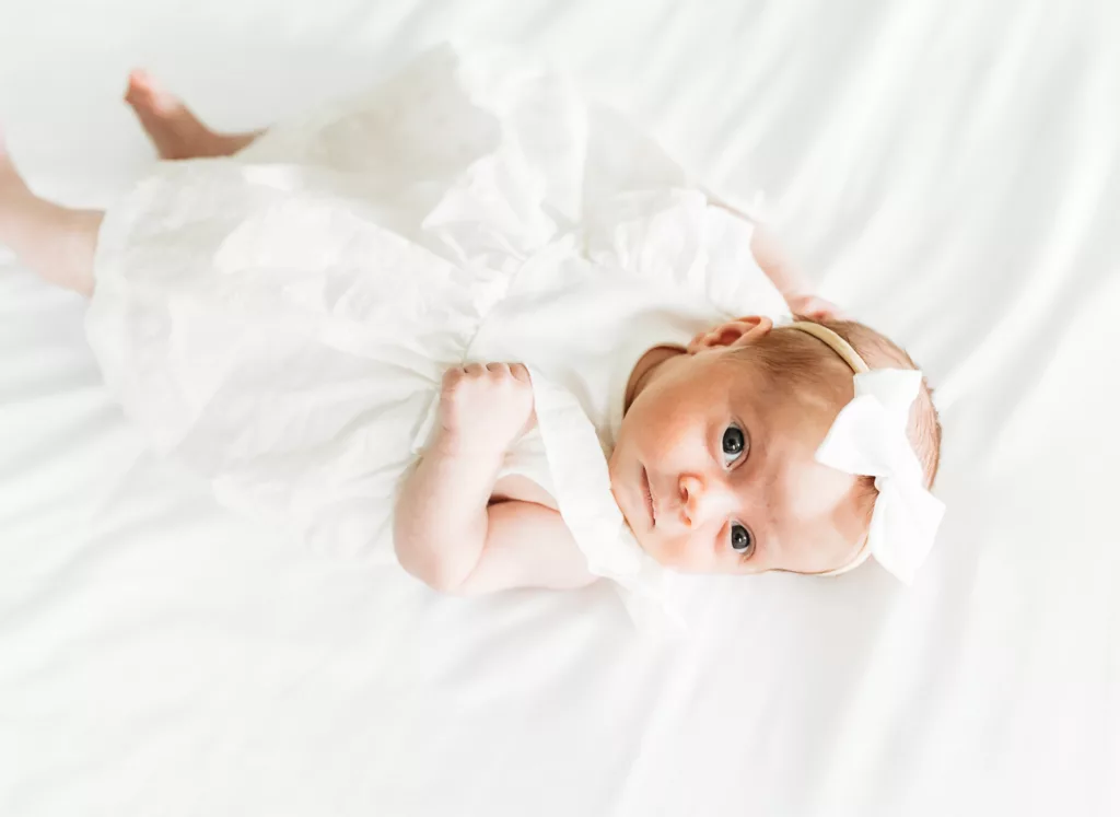 A newborn baby lies on a white background during newborn photo session.