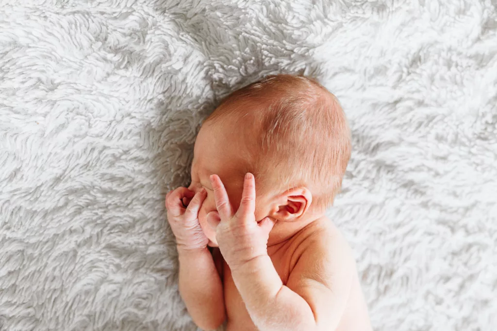 Tiny little newborn covers his face during newborn photos. 