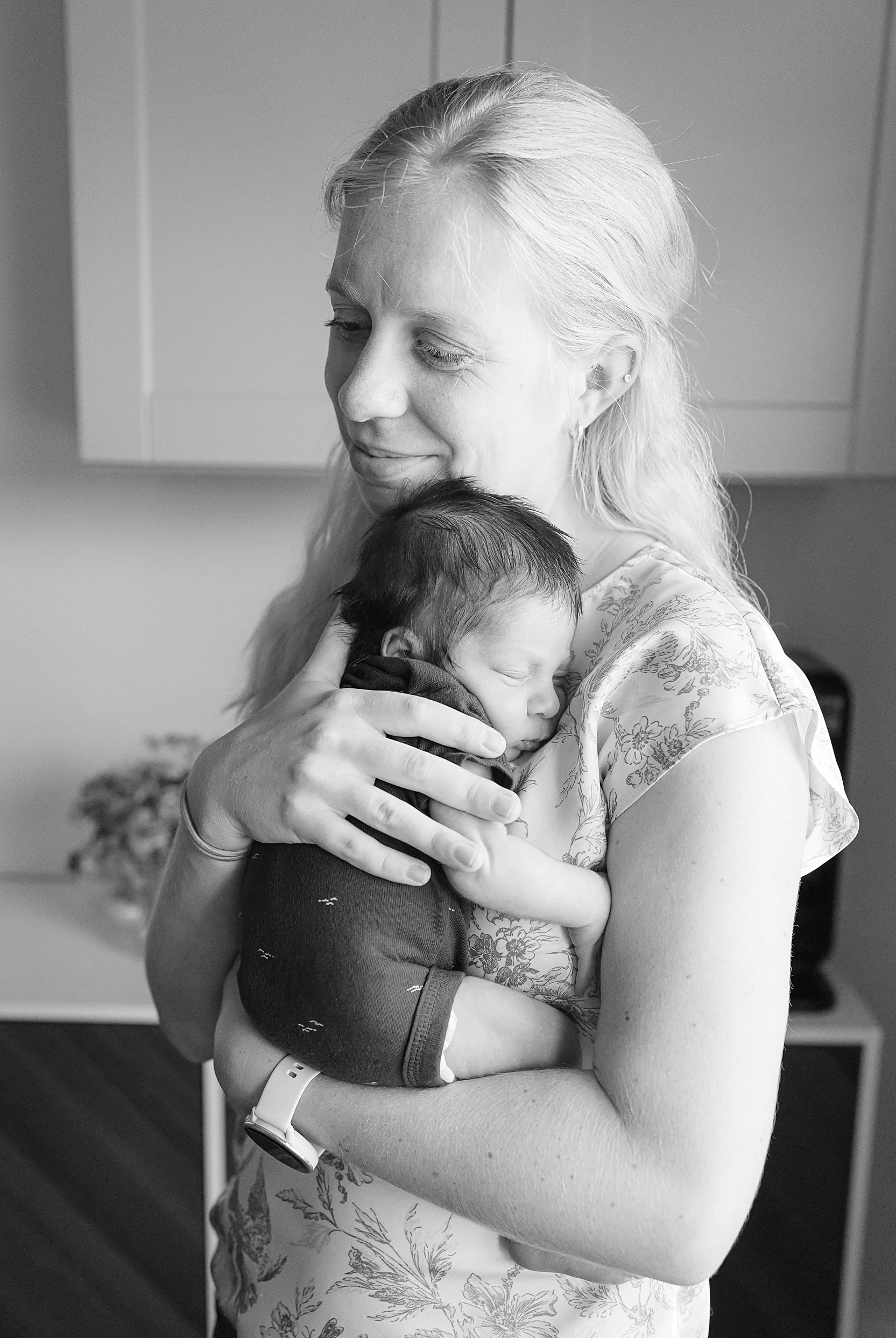 black and white image of mom snuggling a newborn.