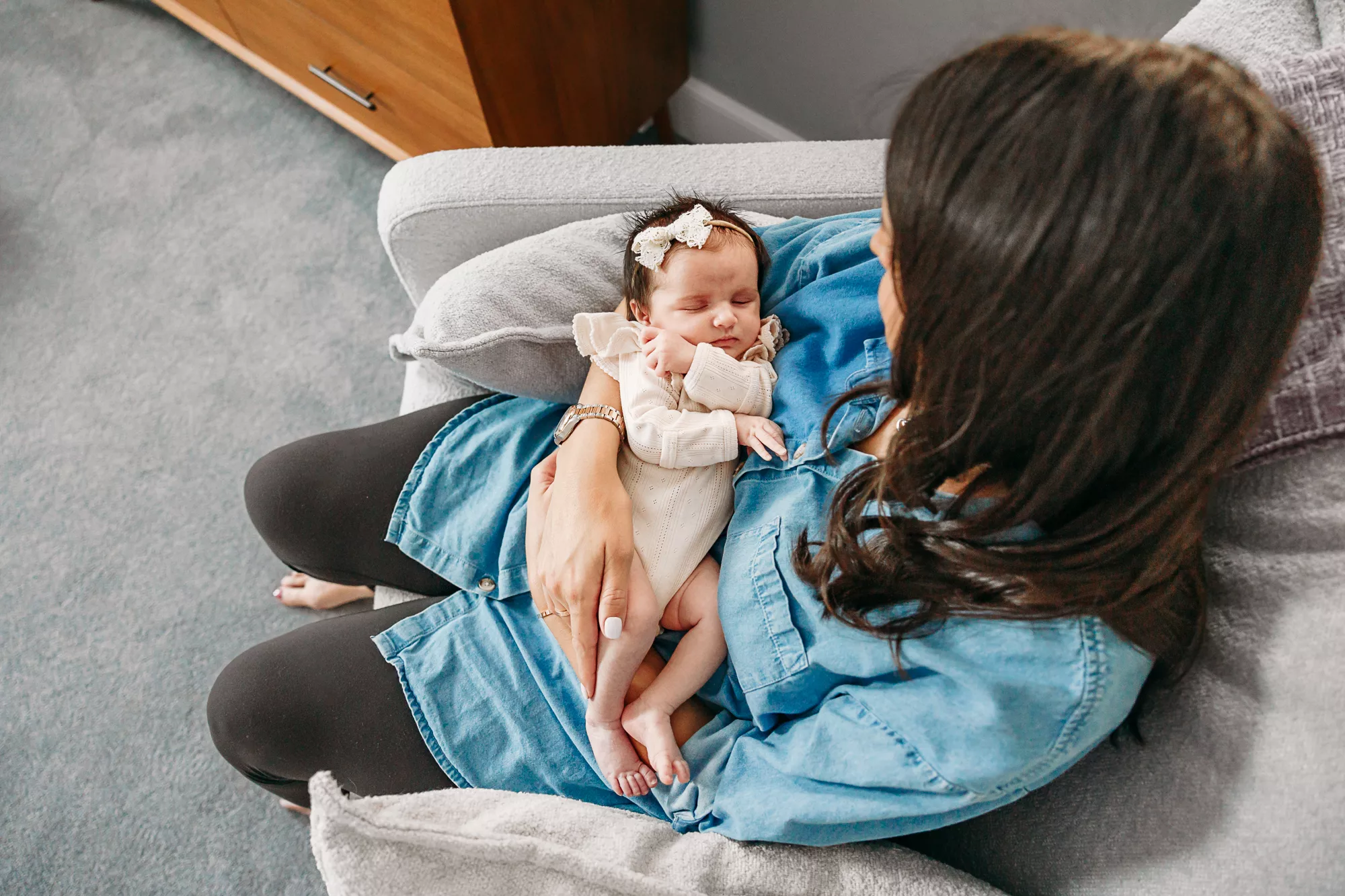 A baby sleeps in her mother's arms during newborn photos.