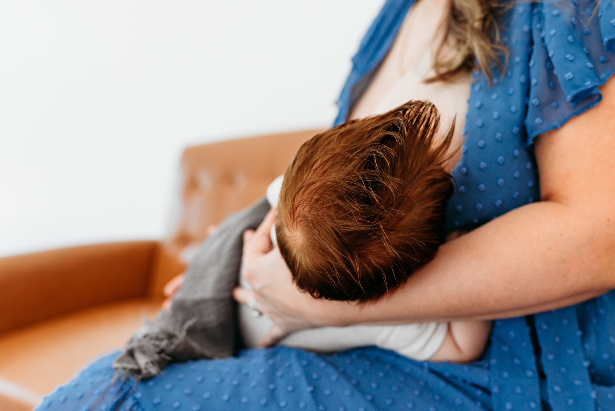 A mother sits to nurse her baby during her OKC mini breastfeeding session.