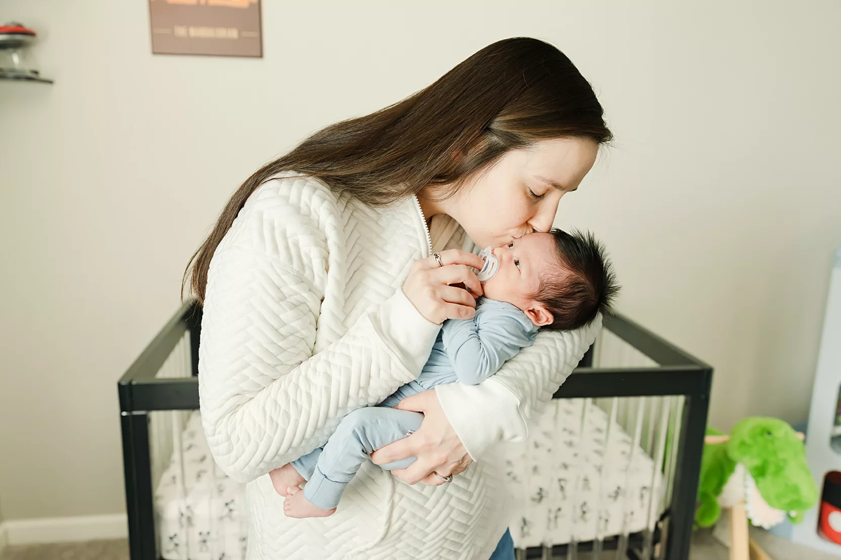 Mom kisses her newborn during an in home newborn photo session.