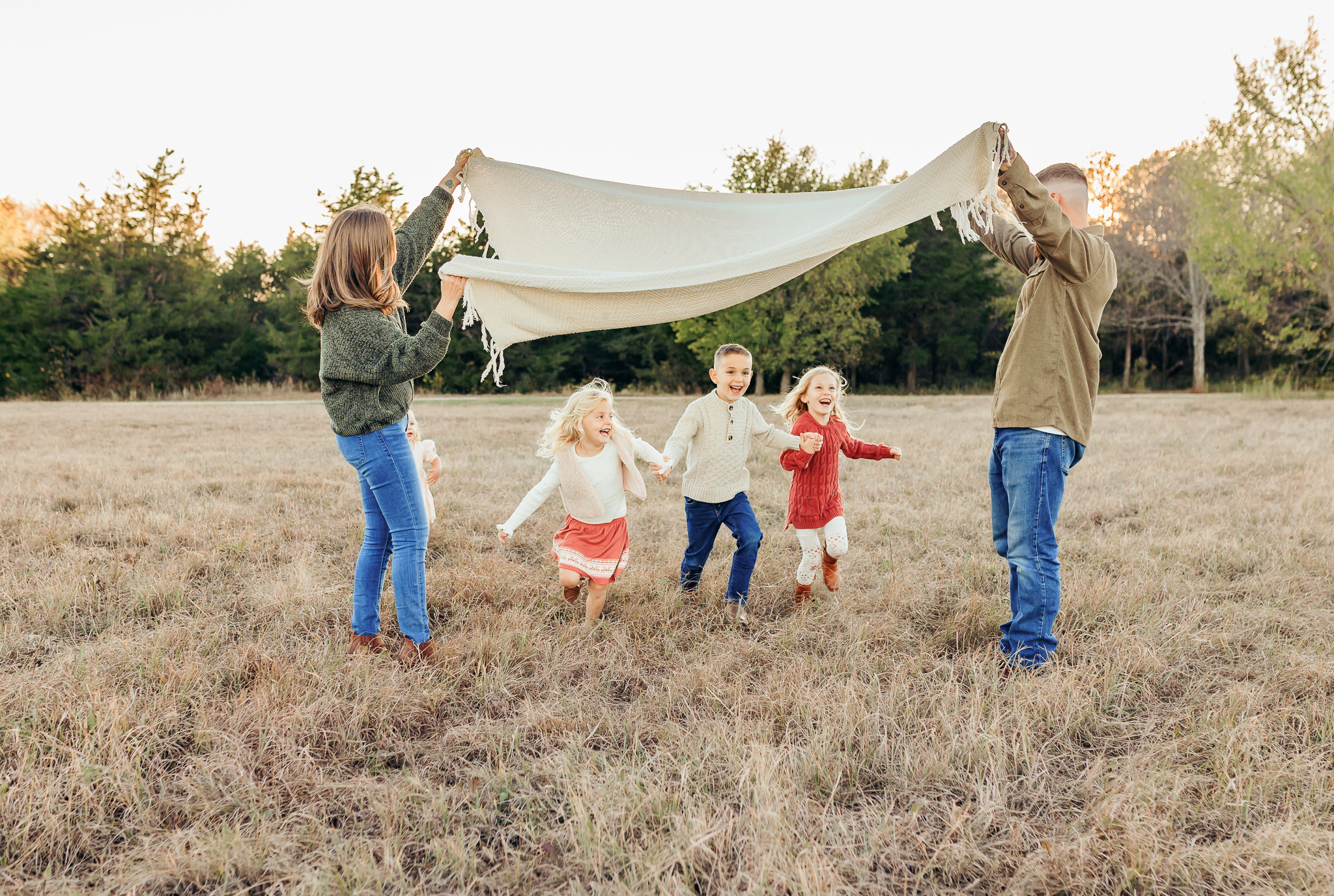 Family runs through field during golden hour at Saxon Park in Norman, OK.