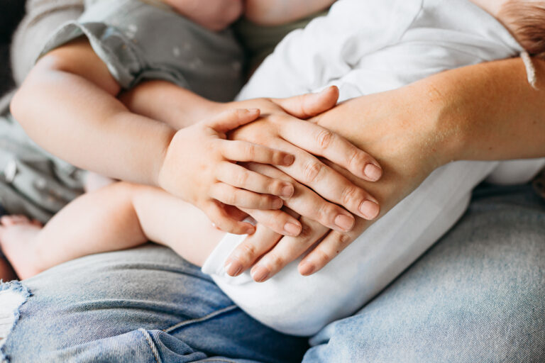 a mama and her little one have their hands stacked on each other.