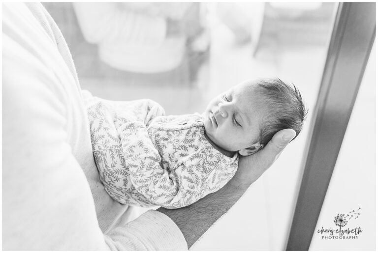 Baby sleeps in dad's arms.