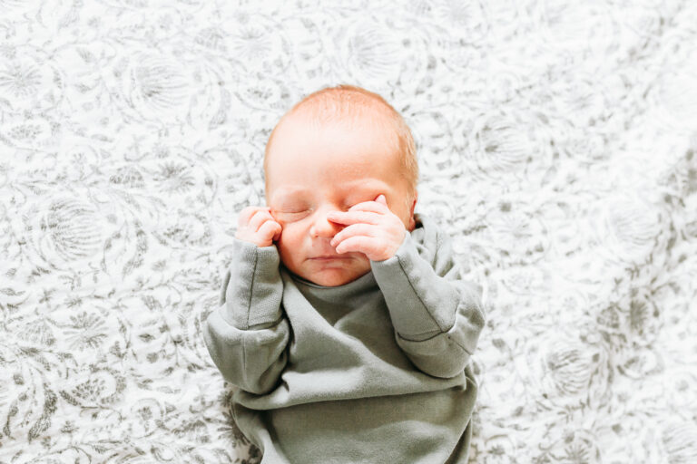 New baby boy on bedroom quilt during newborn session.