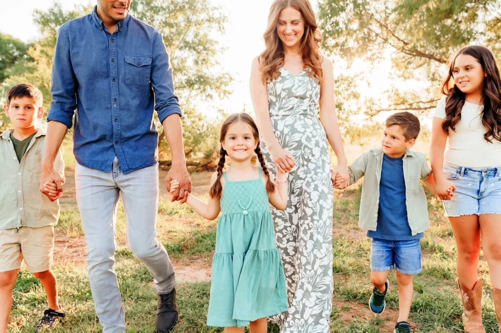 Family of 6 walking through a field during a golden hour session in OKC.
