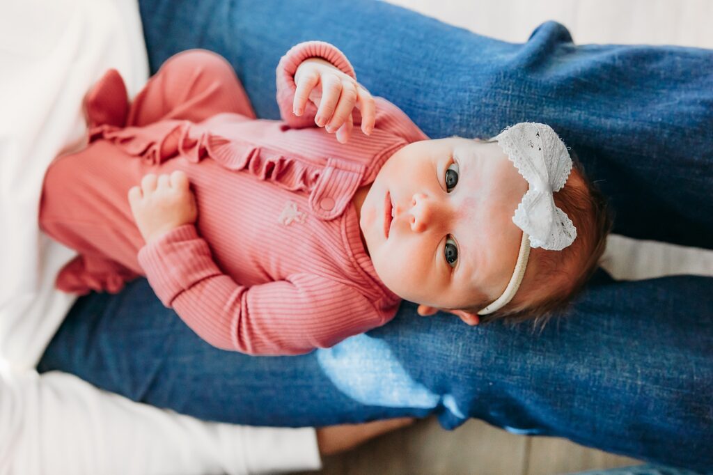 newborn lays in daddy's lap during newborn photos.