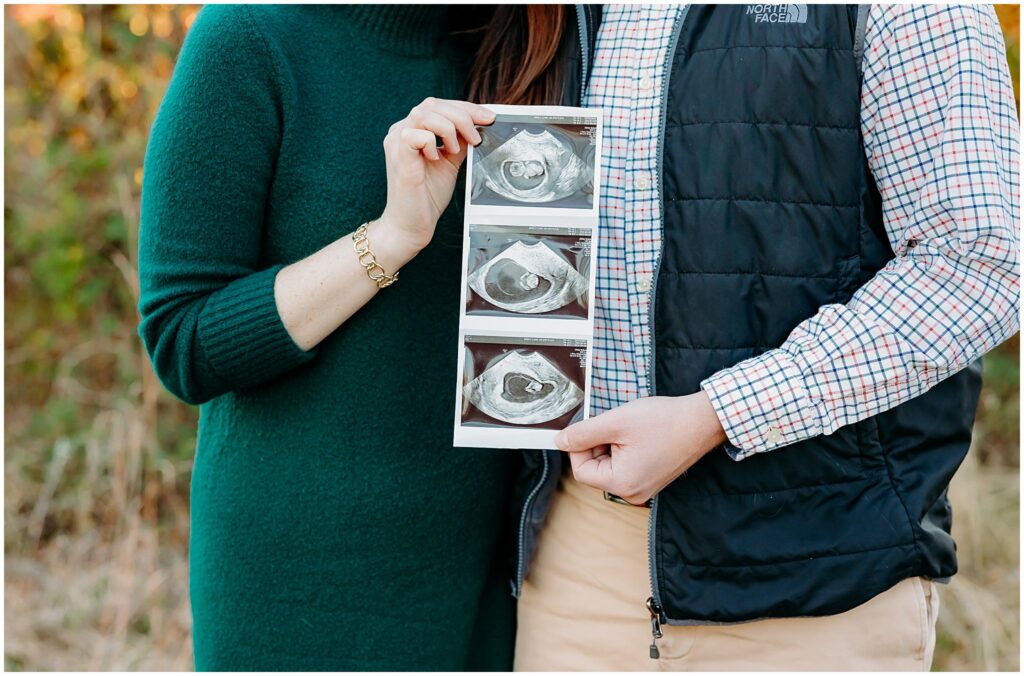 Couple holds ultrasound pictures.