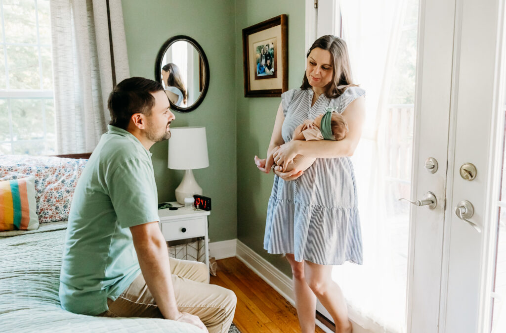 Mom holds newborn and looks at dad during newborn photos.