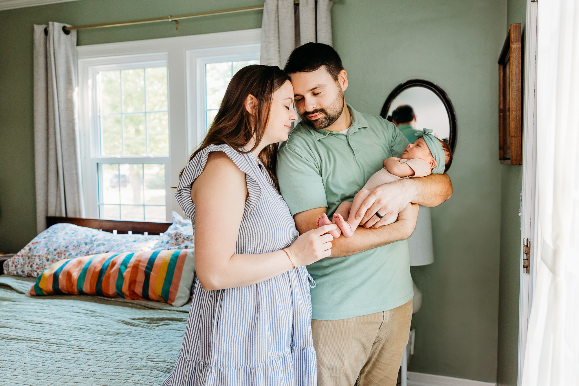 Mom and Dad in white shirts hold baby during newborn photoshoot.