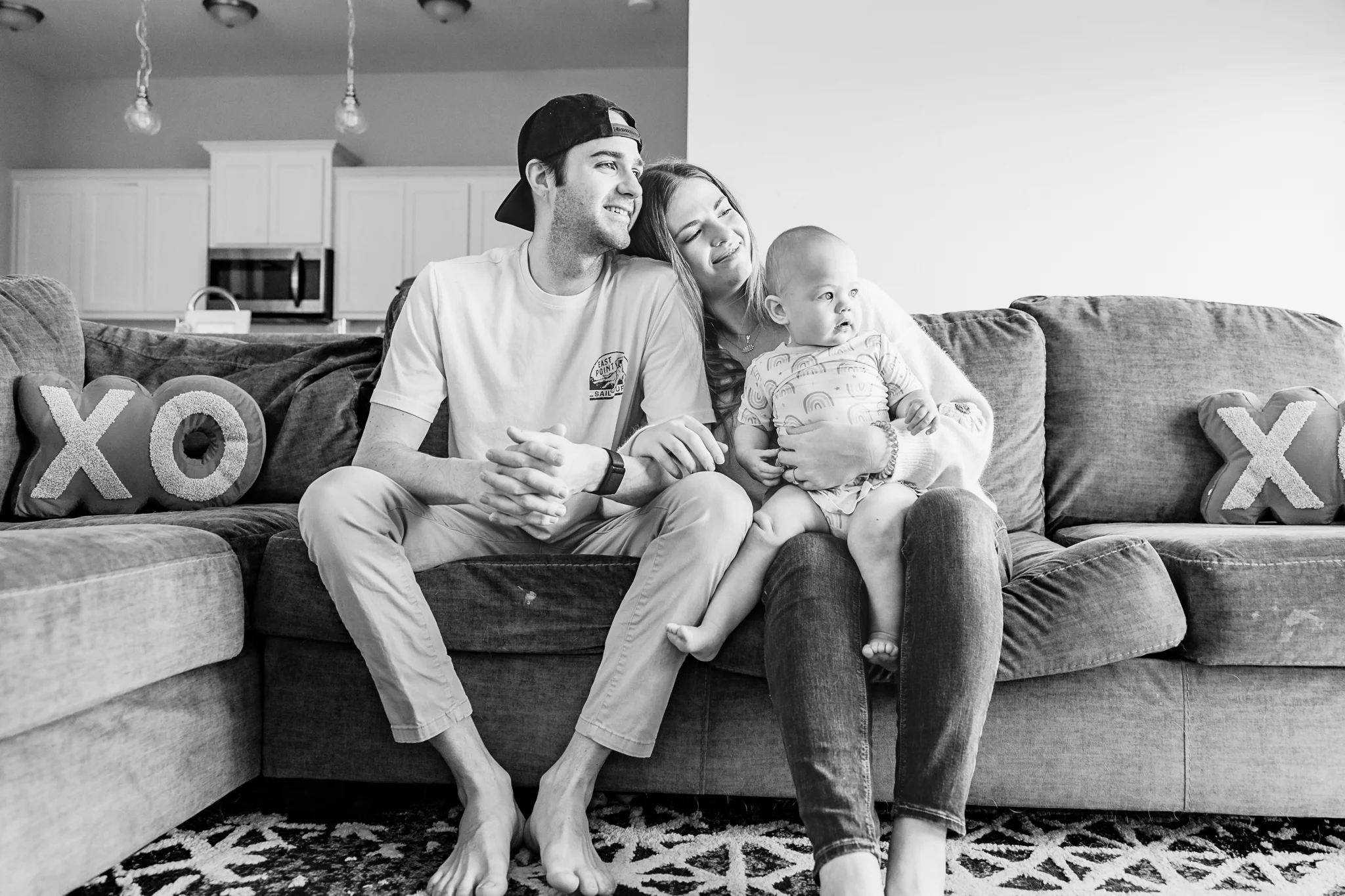Mom and Dad kiss their toddler daughters on the living room floor during at home family photo session in OKC.