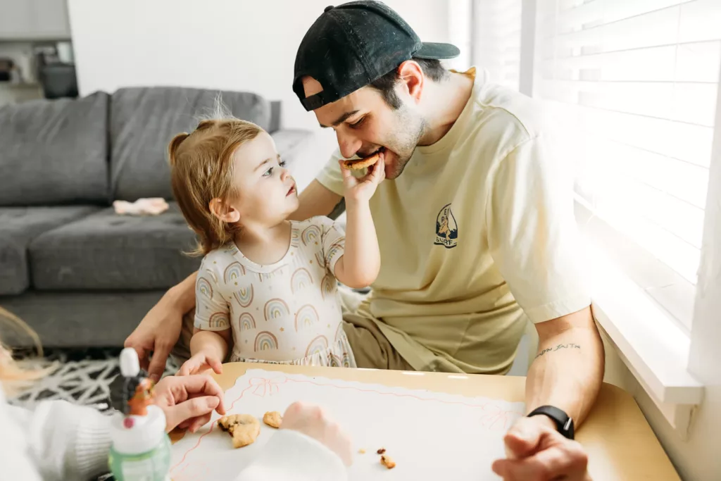 Toddler daughter shares cookies with Daddy during an at home photo session in Yukon, OK.