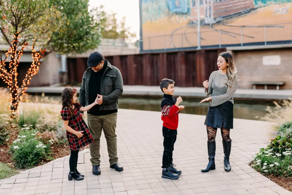Family plays together by Bricktown canal during a fall family photo session.