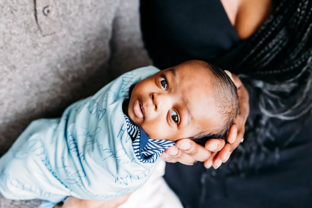 New baby in parents arms during OKC newborn photography session.