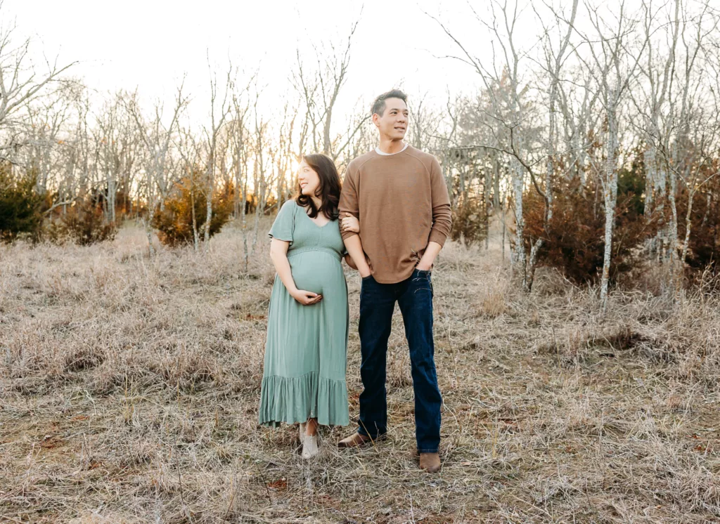 Husband and wife stand together during maternity photo session at Bluff Creek Park in Oklahoma City.
