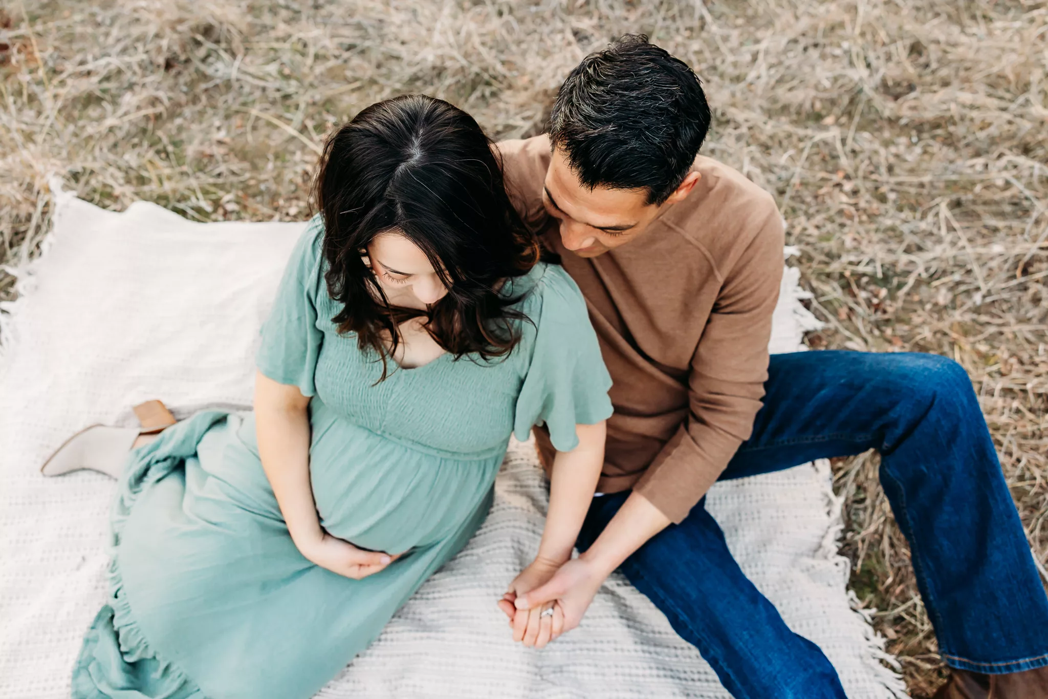 Mom and Dad in white shirts hold baby during newborn photoshoot.