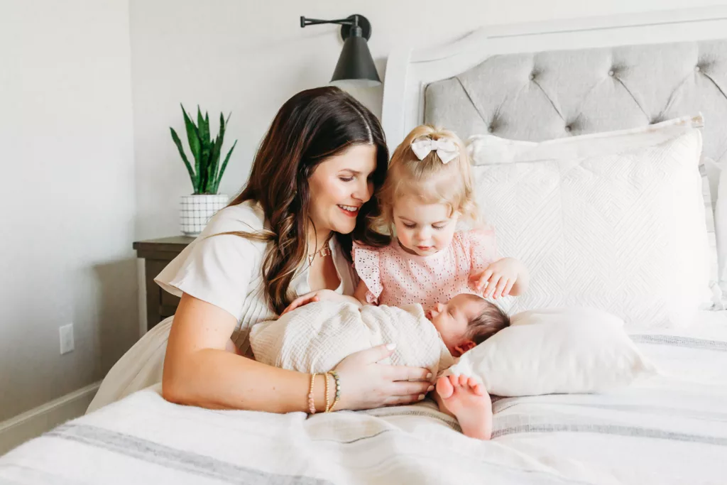 Mom snuggles toddler and newborn during newborn photography session at home in Oklahoma City.