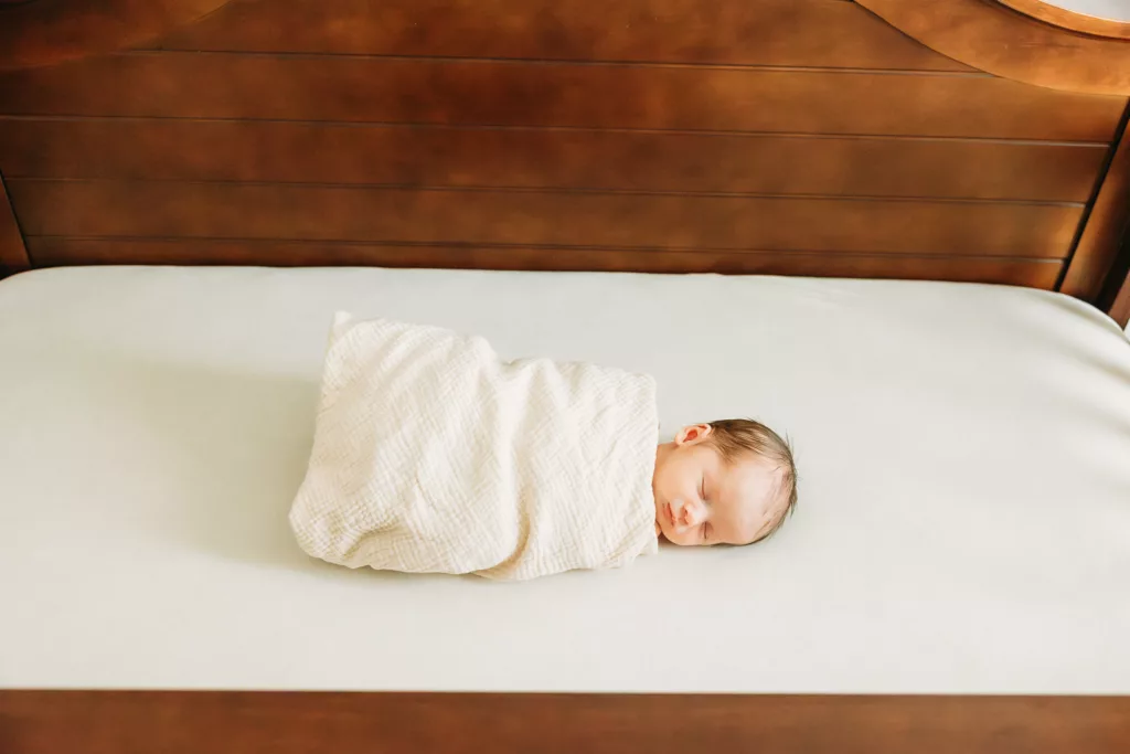 Newborn baby boy lies in crib.