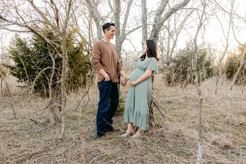 Man and Woman stand together in trees during maternity photo session in OKC.