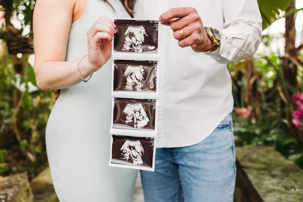 mom and dad hold sonogram picture in hands during photo session.