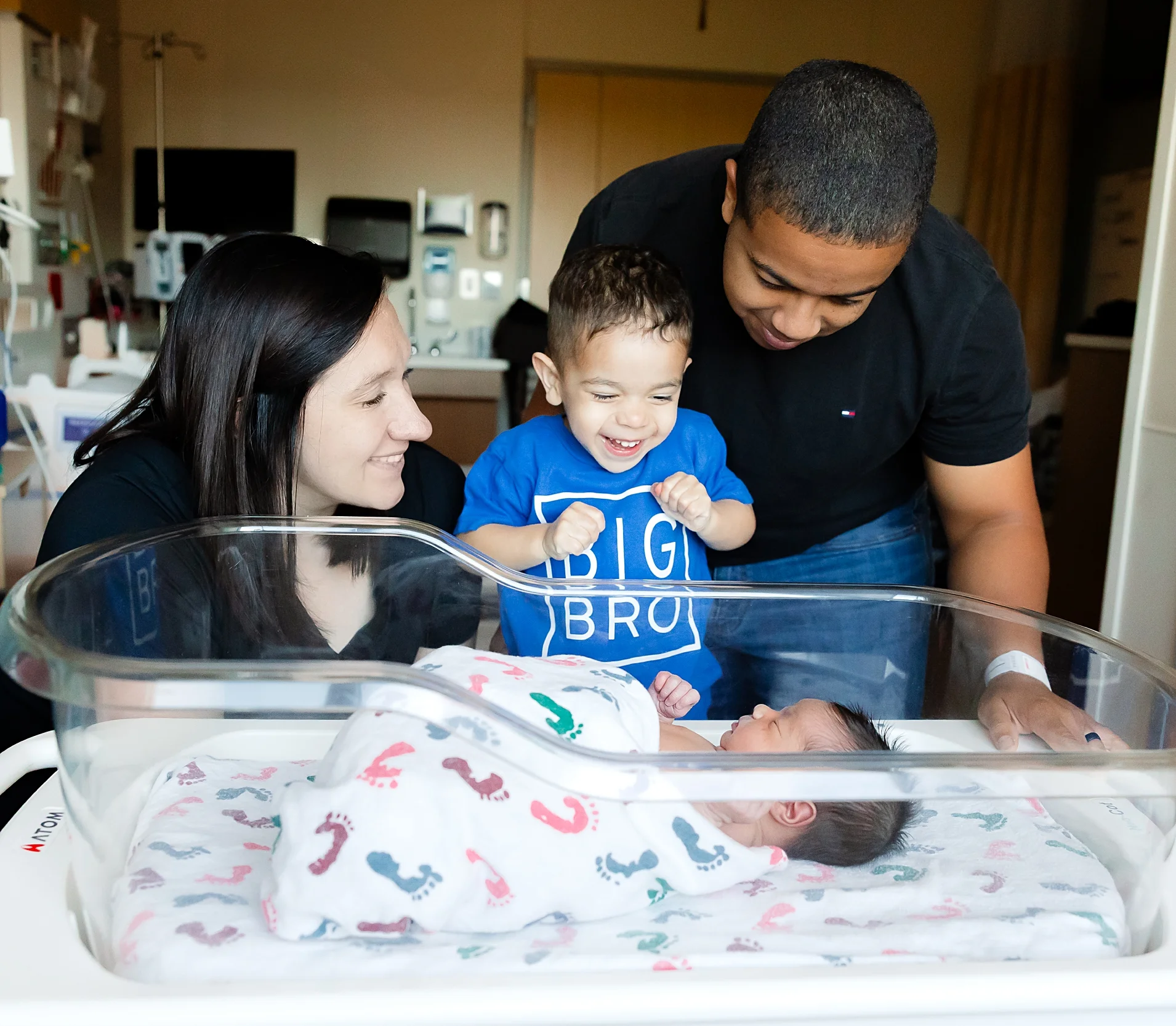 A photo of new parents, new baby and their poodle.