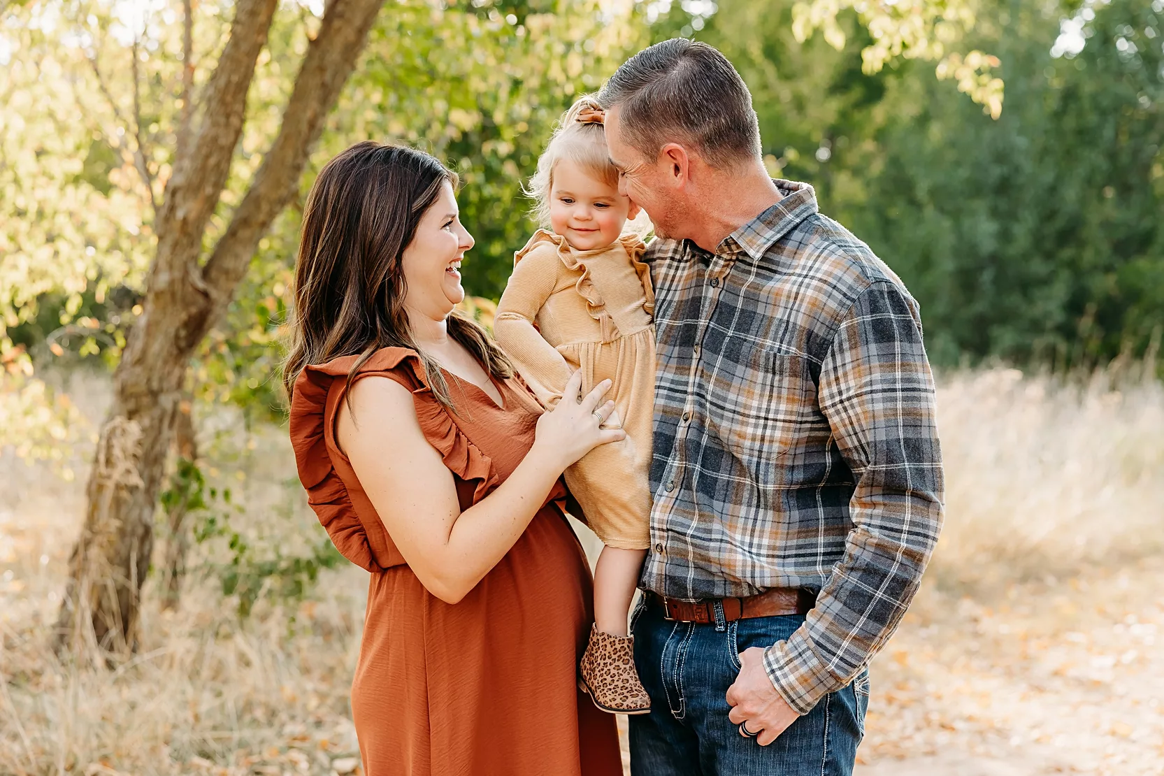 Mom and Dad in white shirts hold baby during newborn photoshoot.