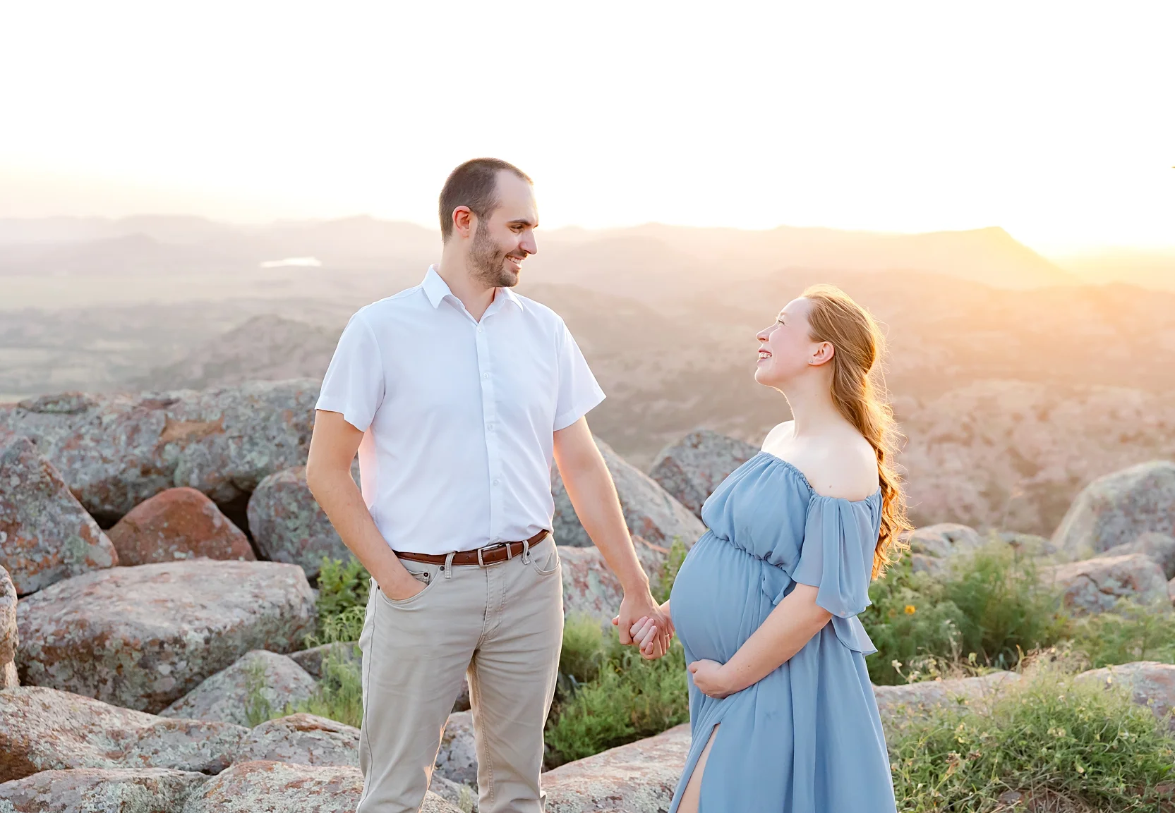 Mom and Dad in white shirts hold baby during newborn photoshoot.
