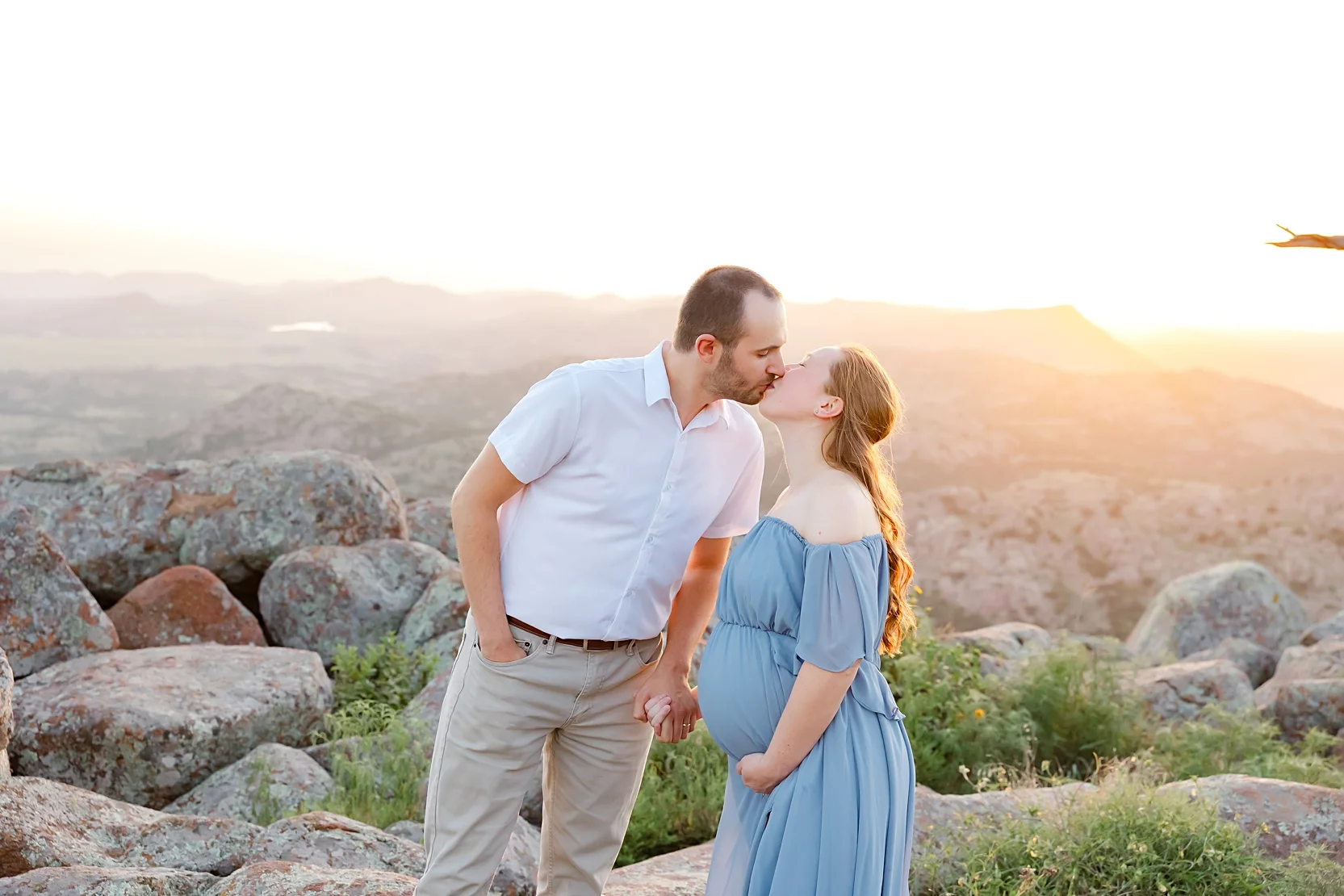 Mom and Dad in white shirts hold baby during newborn photoshoot.