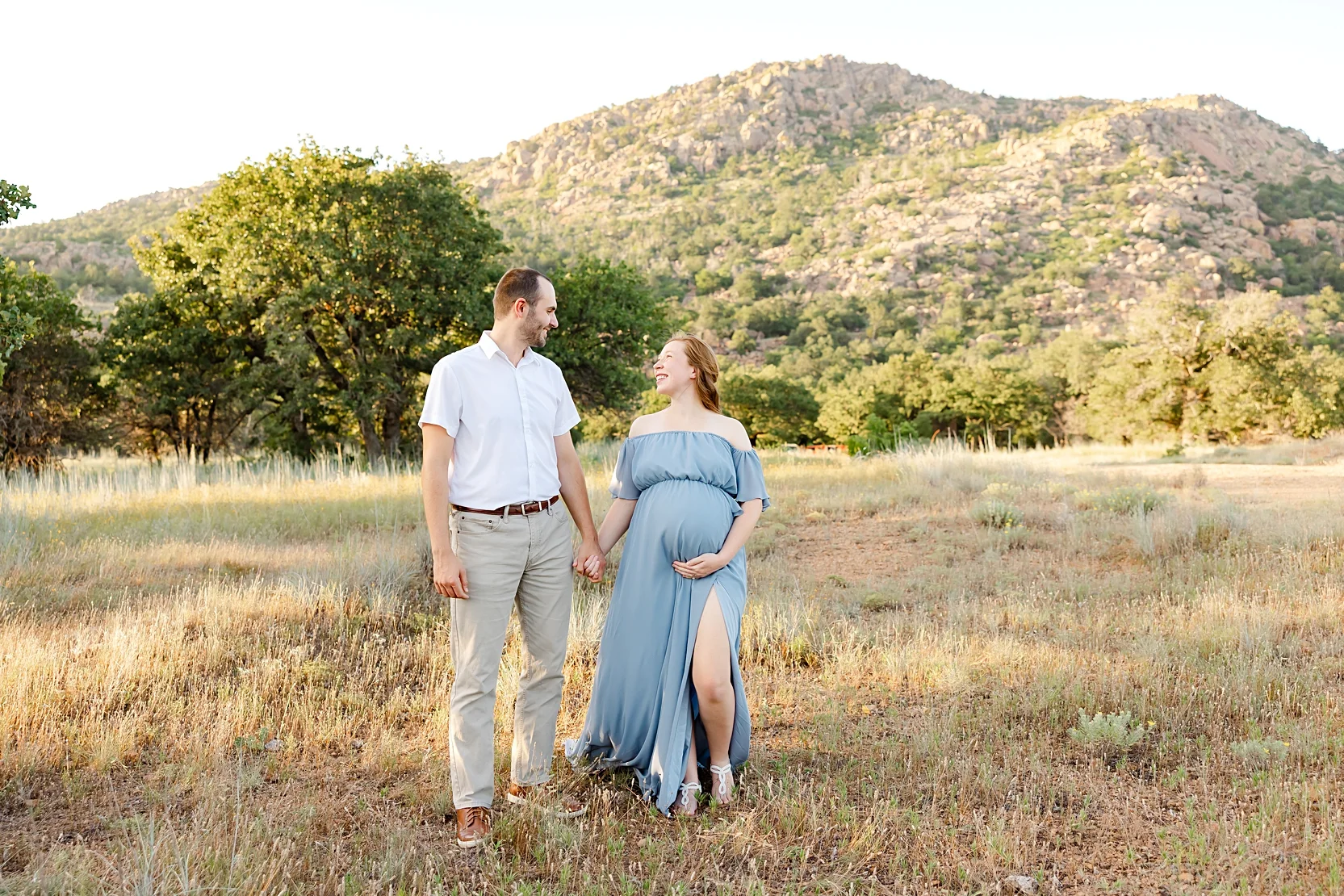 Mom and Dad in white shirts hold baby during newborn photoshoot.