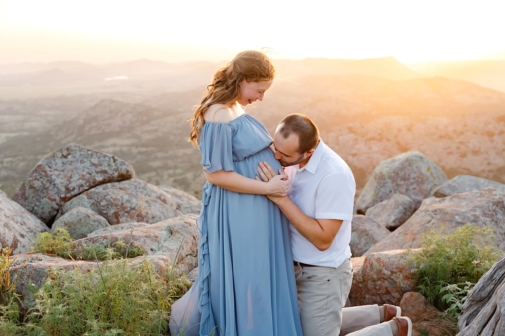 Mom and Dad in white shirts hold baby during newborn photoshoot.