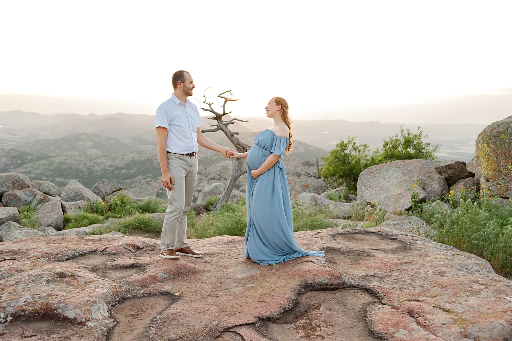 Mom and Dad in white shirts hold baby during newborn photoshoot.