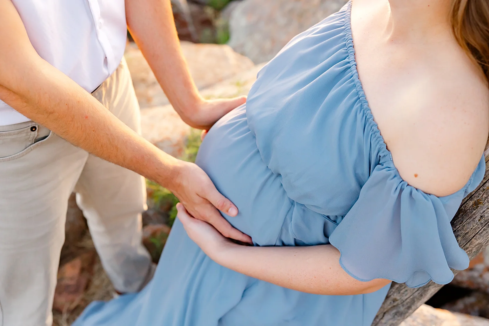 Mom and Dad in white shirts hold baby during newborn photoshoot.