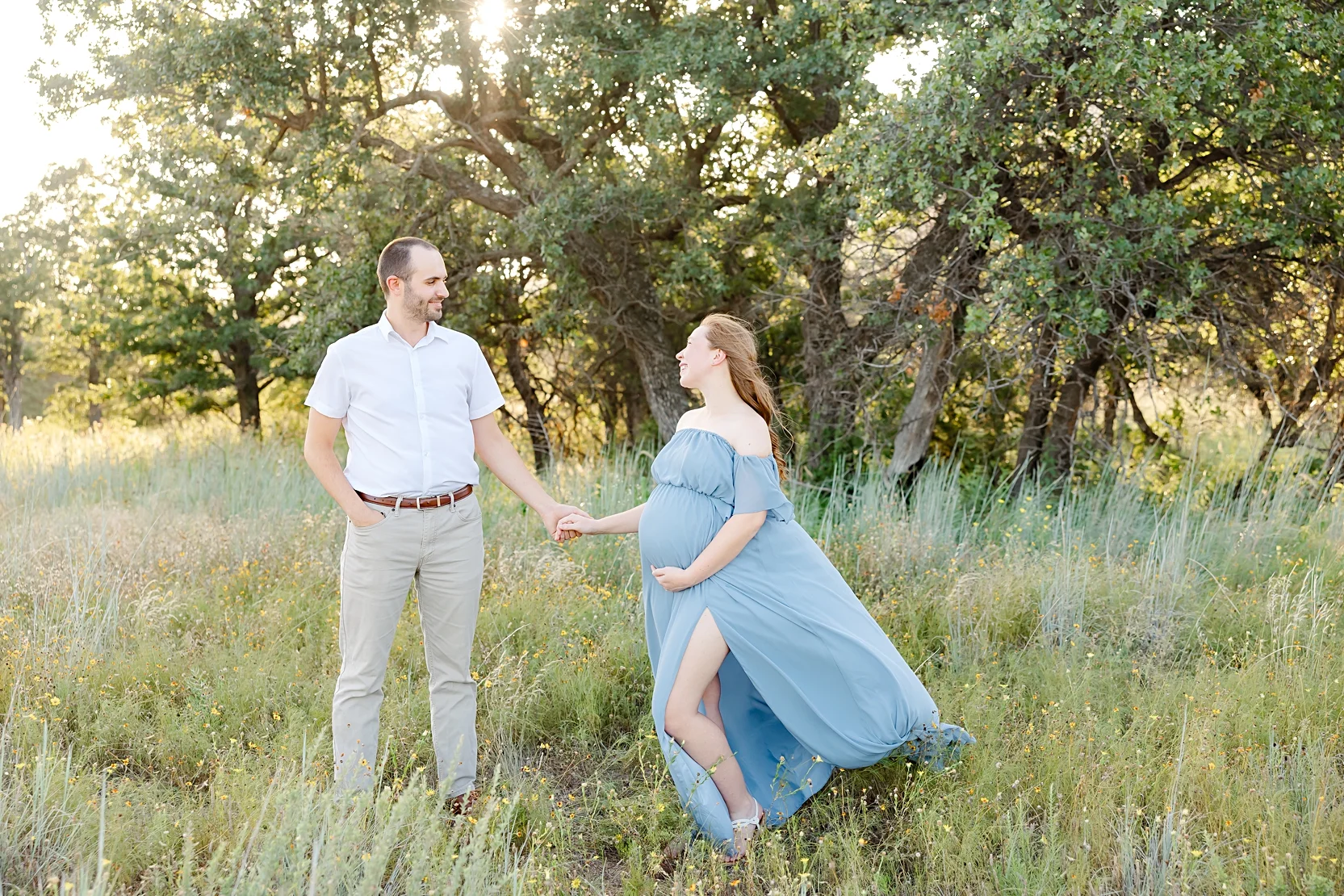 Mom and Dad in white shirts hold baby during newborn photoshoot.