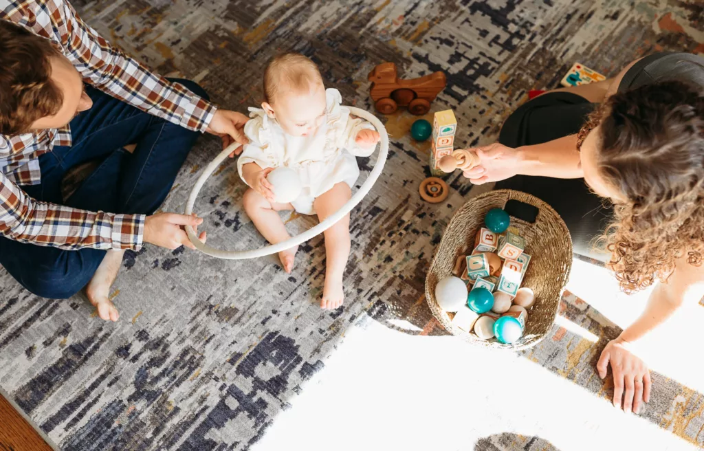 Family of 3 plays together on floor during family photos.