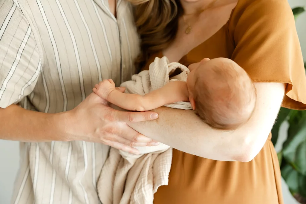 baby holds dad hands during an newborn photography session in OKC.