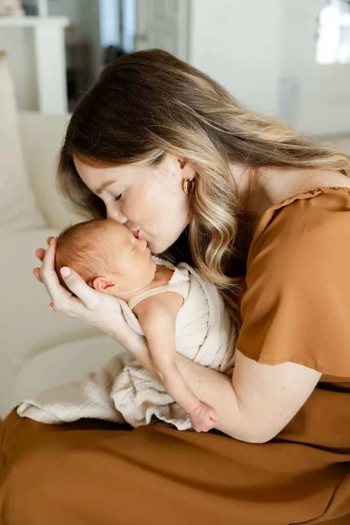 Mother kisses her baby during a new session with Oklahoma City Newborn Photographer Charis Elisabeth Photography.