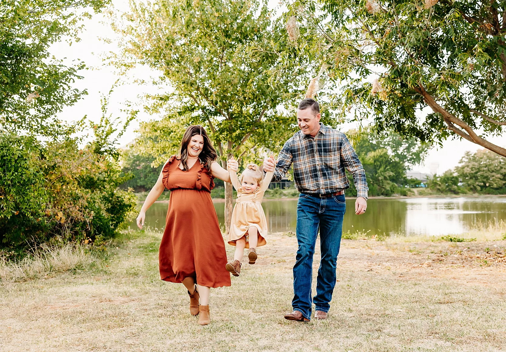 Mom and Dad in white shirts snuggle their newborn in a pink outfit.