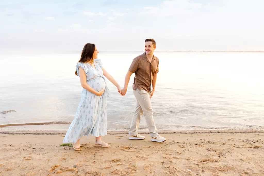Couple walks along Lake Hefner Beach during an early morning maternity photo session in Oklahoma City.