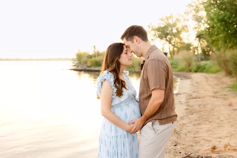 A couple takes maternity photos on Lake Hefner beach in a photo on the post of fall bucket list for expecting moms in OKC.