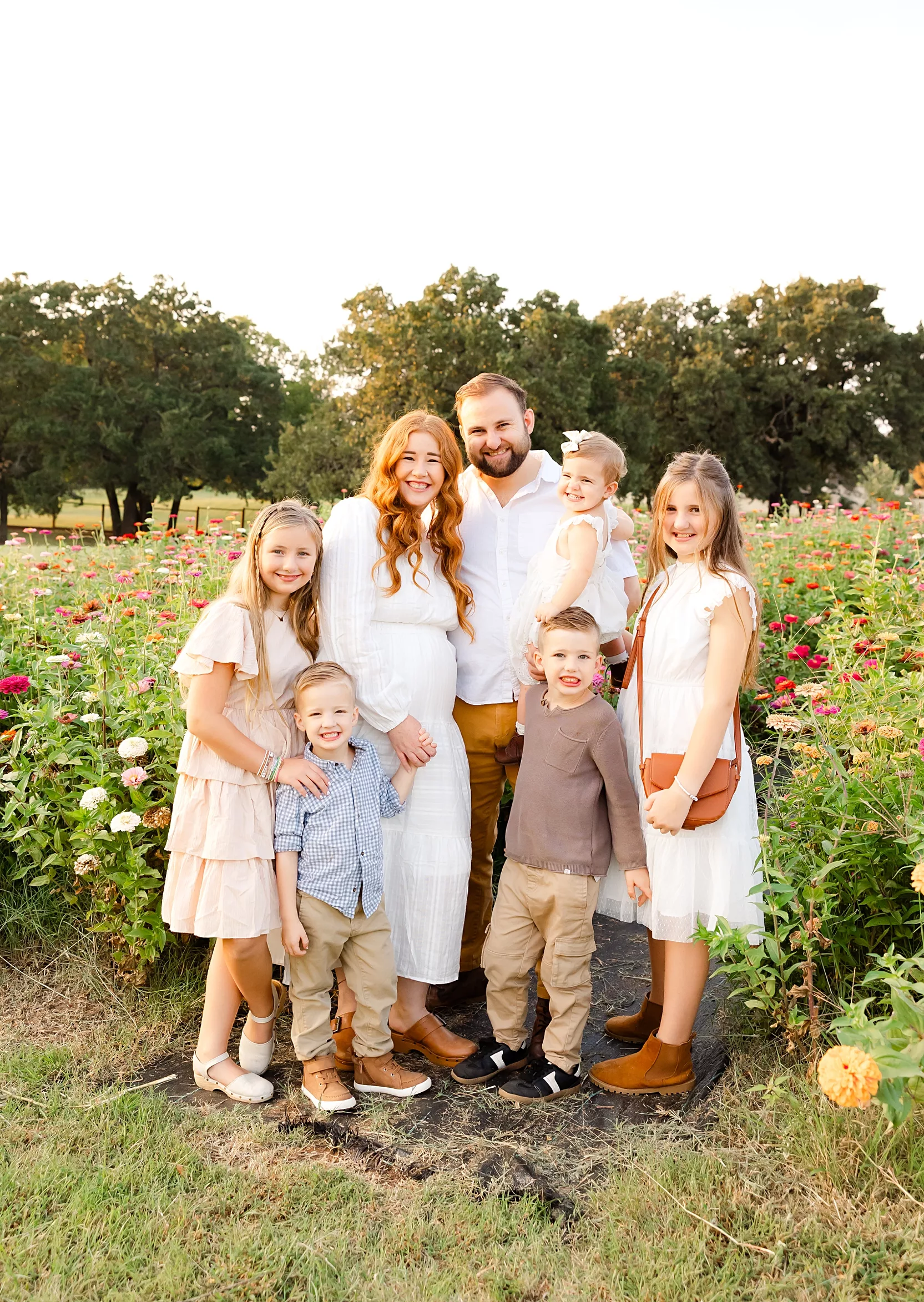 Family of 7 stands in the zinnias at the Grove in Arcadia, Oklahoma during a family photo session.