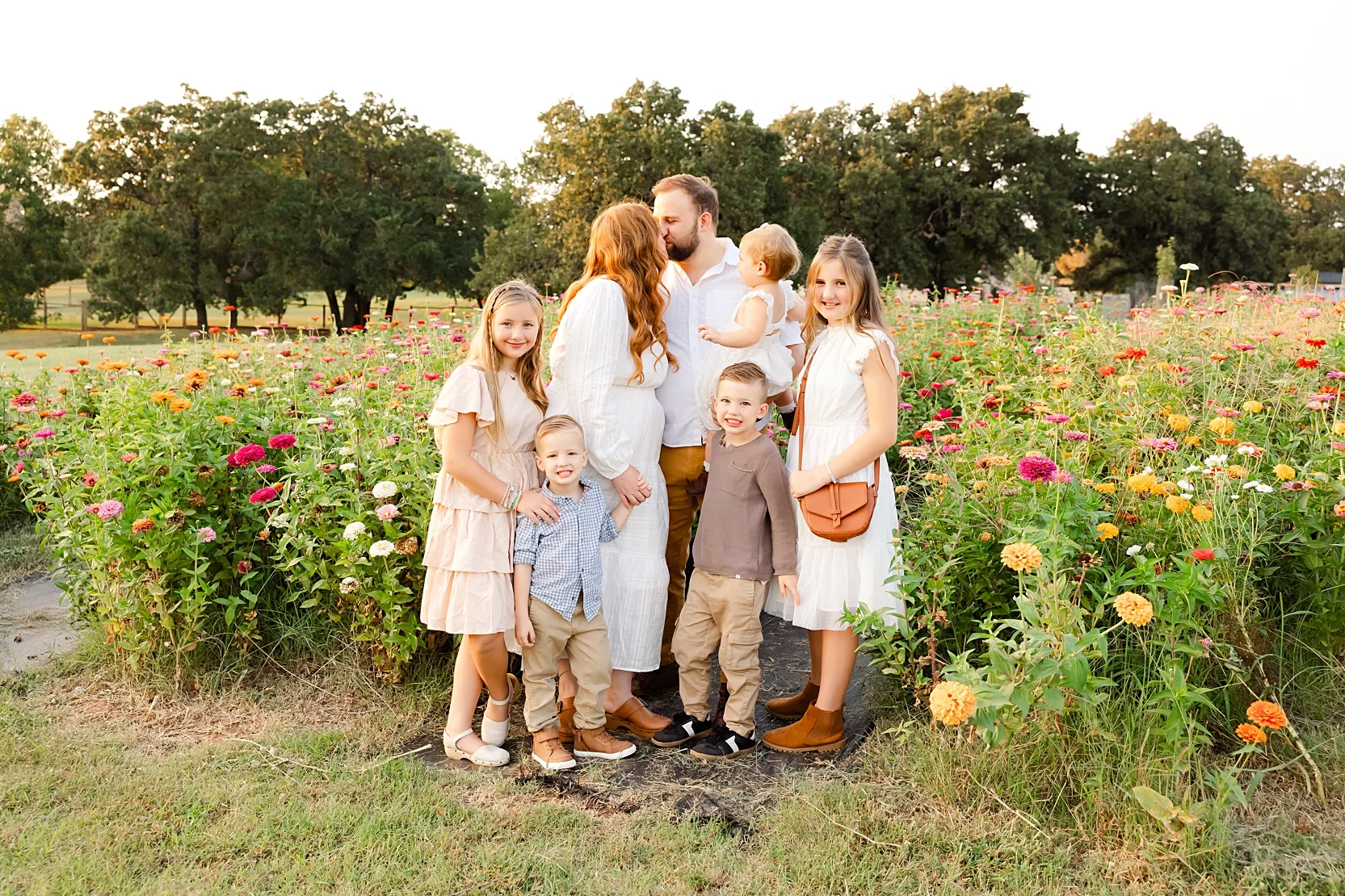 A new mom and dad stand in their living room with a newborn during their lifestyle baby photo session in OKC. 