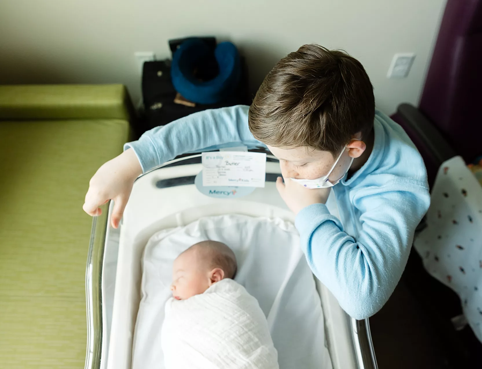 Big brother looks at baby during hospital newborn photos in Oklahoma City.