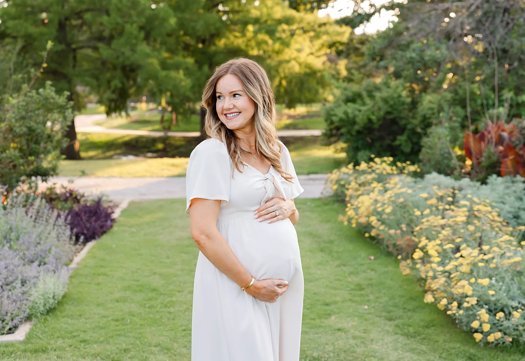 Mom holds bump in golden sunset session at Will Rogers Botanical Gardens in Oklahoma City, OK.