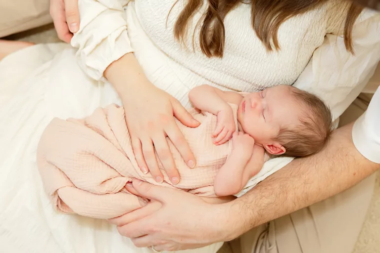 baby girl wrapped in pink in her parents arms.