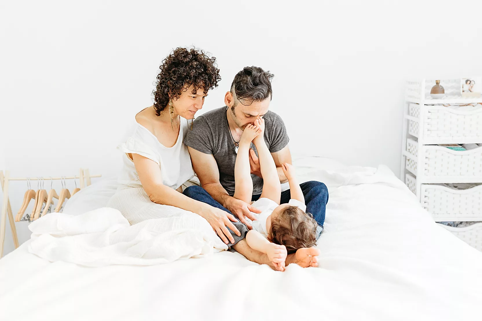 family of 3 plays on bed during in home family photo session
