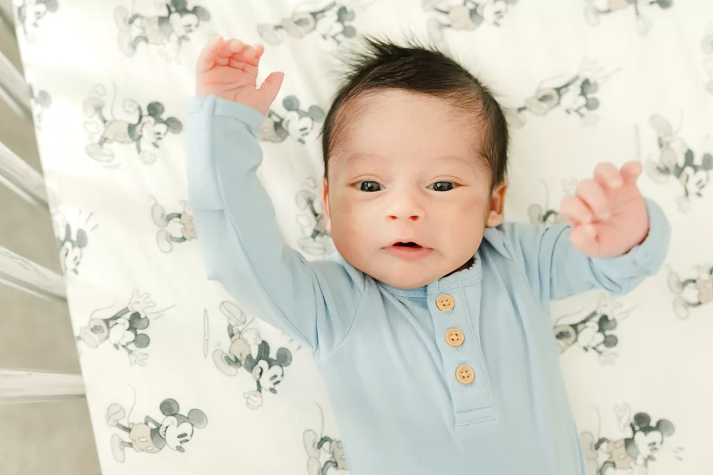 Baby boy waves hello during his newborn photography session.