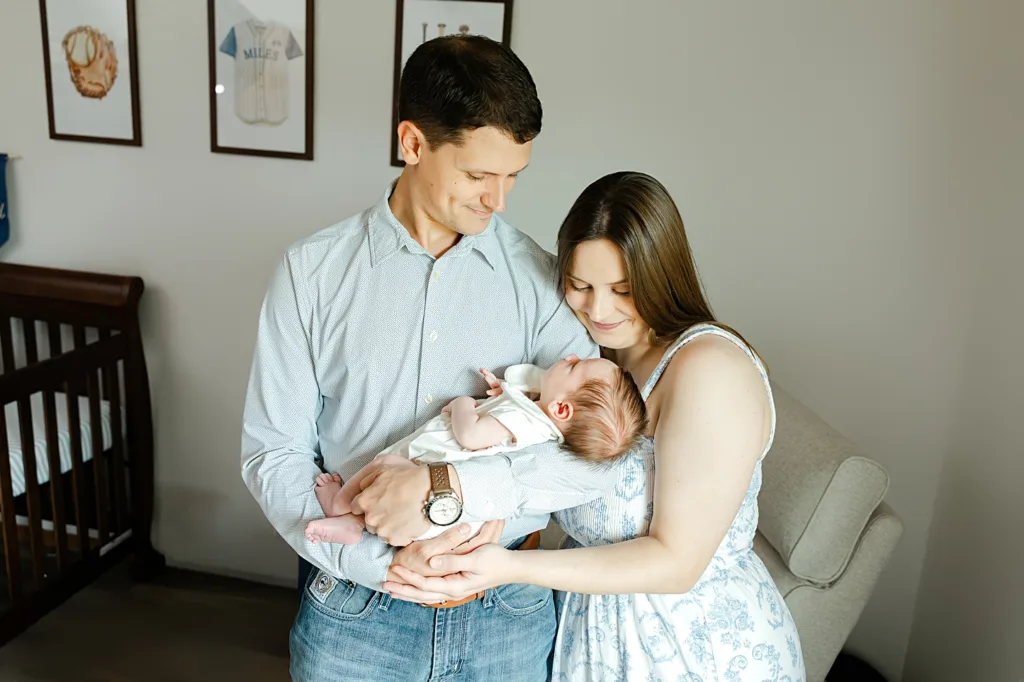 Mom and Dad look at baby boy during OKC baby photos at home.